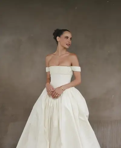 Bride in an off-the-shoulder ivory ball gown, hair drawn up into a sleek high bun