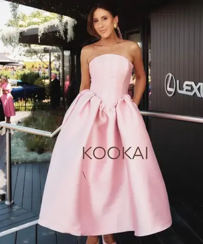Guest outside a raceday marquee in a strapless blush pink gown with a full skirt, dark hair pinned into a sleek chignon