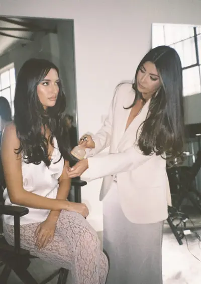 Gabrielle in a cream suit working on a seated client's long dark hair in the salon