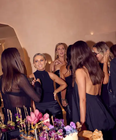 A group of guests in black evening dresses talking together in the salon at an evening event