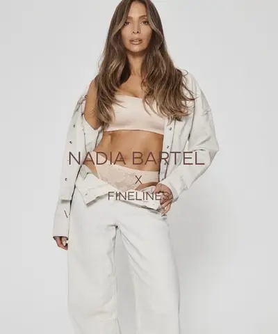 Model in a cream jacket and wide-leg trousers against a plain pale backdrop, hair in long loose waves