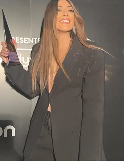 Gabrielle holding an award on stage, in a black tailored jacket