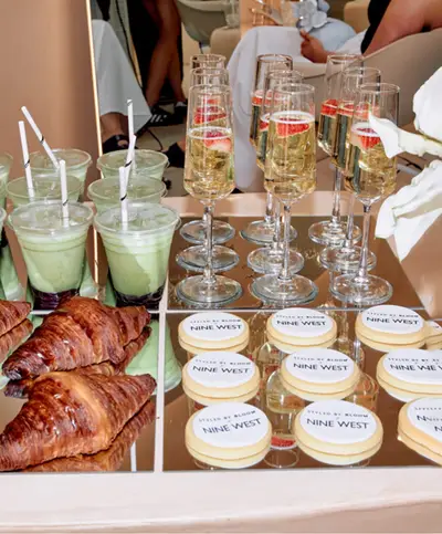 Champagne flutes, green smoothies, croissants and branded iced biscuits set out on a tiered stand