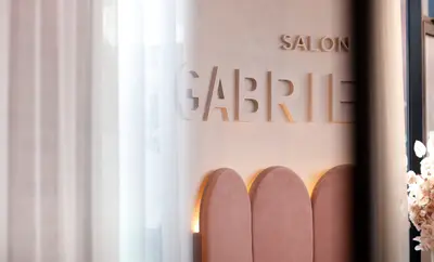 Salon Gabrielle lettering and the arched velvet banquette glimpsed through a sheer curtain